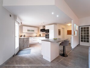 Une cuisine moderne avec des meubles blancs, un îlot central et un tabouret de bar.