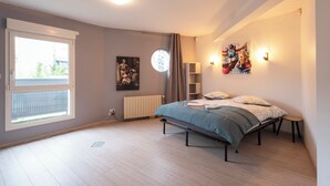 Ein Schlafzimmer mit Bett, Heizkörper, Fenster und einem Bild an der Wand.