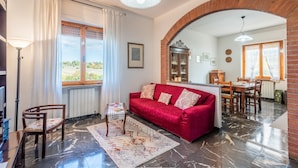 Una sala de estar con un sofá rojo, un comedor con muebles de madera y vistas al exterior.