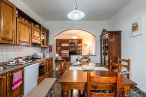 Una cocina con armarios de madera, una mesa de comedor, sillas, un microondas y un lavabo.