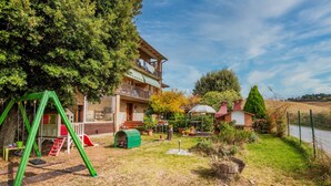 Una casa con balcón, un columpio y un jardín con estanque.