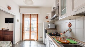 A kitchen with a dining area, a TV, and a door leading outside.