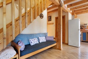 A wooden staircase with a blue sofa and pillows in a room with a white refrigerator and wooden cabinets.
