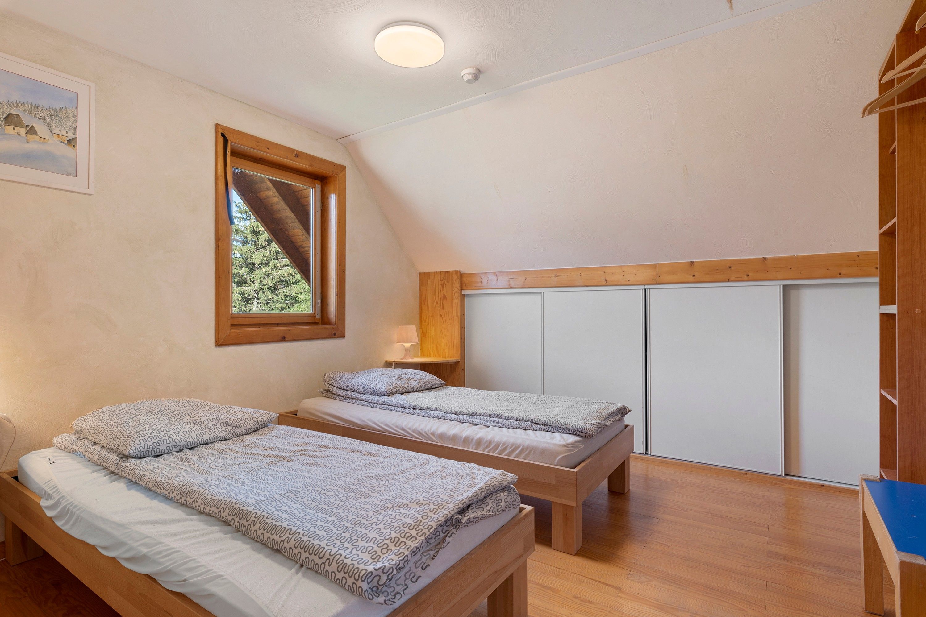 Ein Zimmer mit zwei Holzbetten, einem Fenster und einem Kleiderschrank.