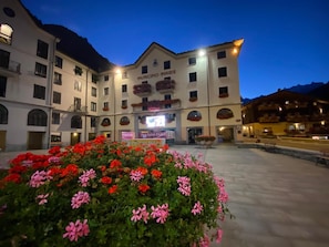 Un hotel con un cortile centrale, aiuole fiorite e un cartello con la scritta 'MUNICIPIO - AIRIE'.