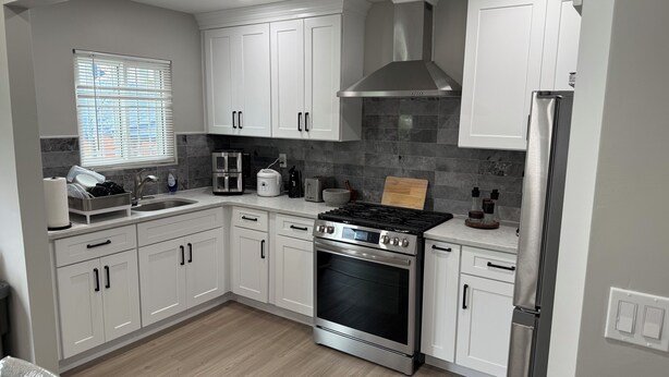 A modern kitchen with white cabinets, a stainless steel range, and a built-in oven. - Peaceful cozy 3-bedroom house with AC in Queens. (Queens)