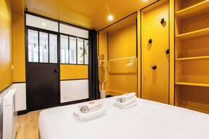 A hotel room with a bed, two towels, a wardrobe, and a mirror. - Chic Apartment - 1br/4p - Centre de Paris (Paris)