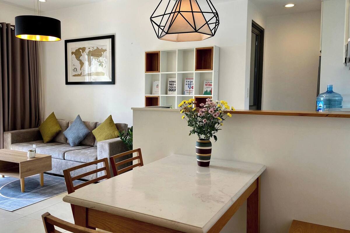 A modern living room with a sofa, a coffee table, a dining table, and a vase with flowers.