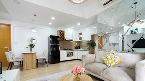 A modern living room with a beige sofa, a coffee table with flowers, and a dining area with chairs and a small table. - Cherry Houses - Masteri Thao Dien (Ho Chi Minh City)