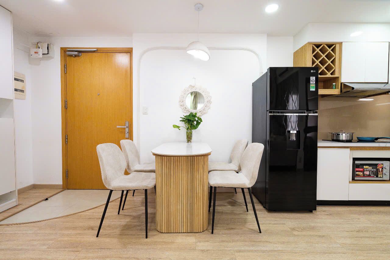Una cocina moderna con un refrigerador negro, un armario de madera y una mesa redonda con sillas.