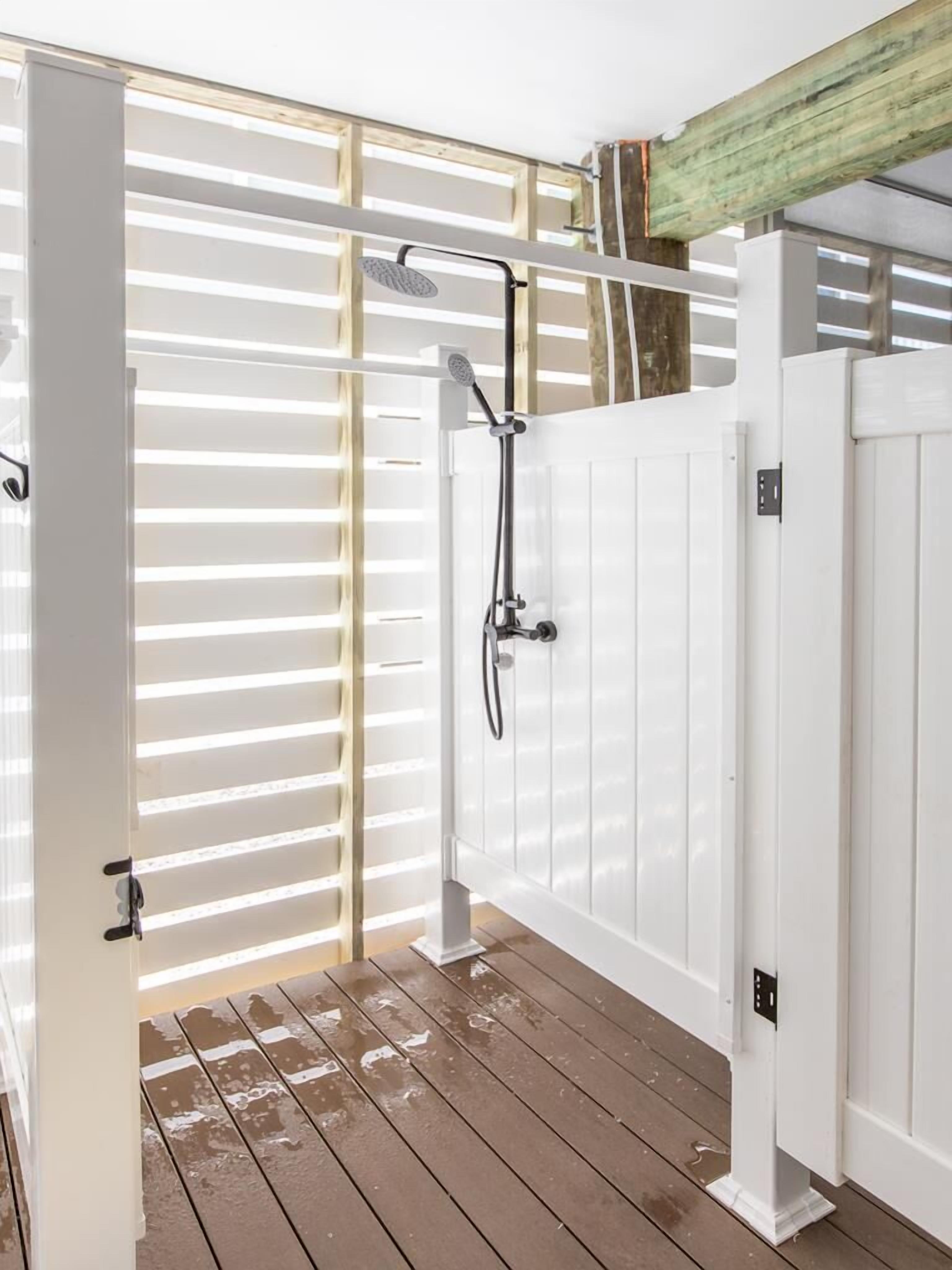 Une terrasse en bois avec une porte blanche et un espace douche.