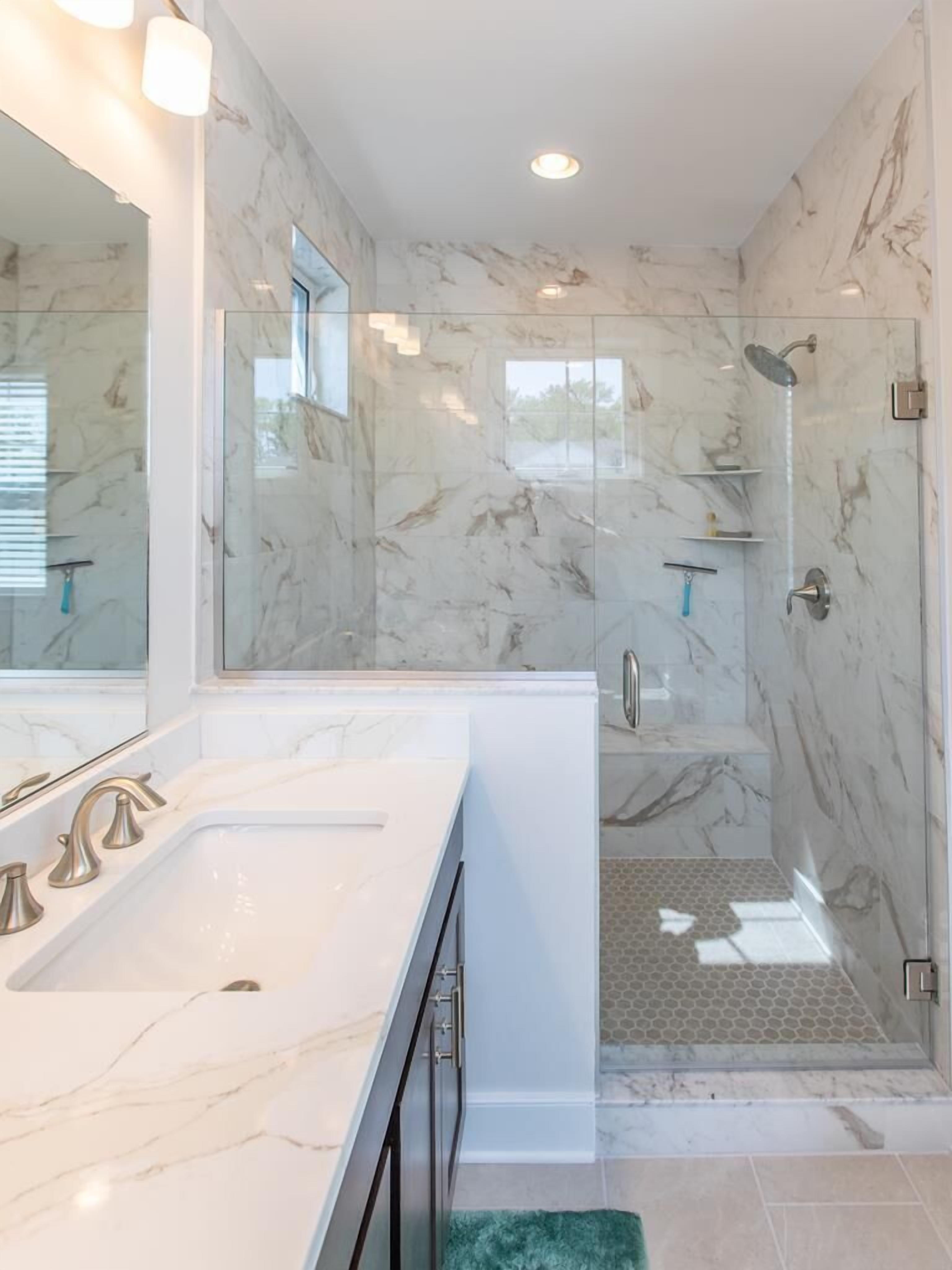 A modern bathroom with a large mirror, a double sink vanity, and a glass-enclosed shower area.
