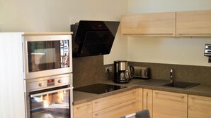 Une cuisine compacte équipée d’un four encastré, d’une machine à café et d’un grille-pain.