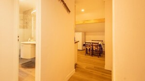 Un pasillo estrecho con piso de madera que conduce a un comedor con una mesa y sillas.