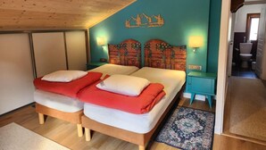 Un dormitorio con dos camas, techo de madera, pared de acento color turquesa y diseño de montaña.