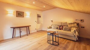 A cozy living room with a wooden ceiling, a sofa with a blanket, a small table, and wall-mounted lights. - 2nd floor, balcony, ski locker, 48m², Valloire (Valloire)