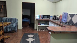 Een knus woongedeelte met een kitchenette, een bank, een bed en een kleine eettafel.