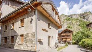 A traditional chalet-style building with stone walls and wooden balconies, set in a mountainous area with a clear sky. - 350m from ski lifts, 2nd floor, parking, 61m², Valloire (Valloire)