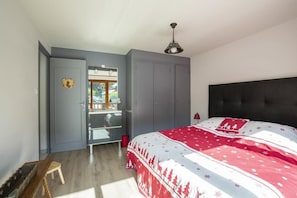 A bedroom with a bed, a wardrobe, a mirror, and a window.
