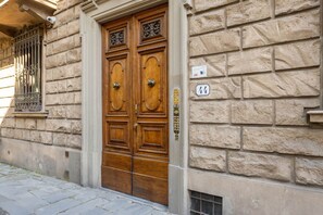 Una puerta doble de madera con manija de latón, ubicada en un edificio de piedra con una placa con el número 44.