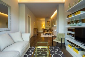 Una sala de estar moderna con un sofá, una mesa de centro, una zona de comedor con sillas y una estantería con objetos decorativos.