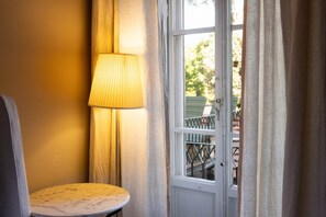 A room with a round table, a lamp, and a door leading to an outdoor area with a railing.