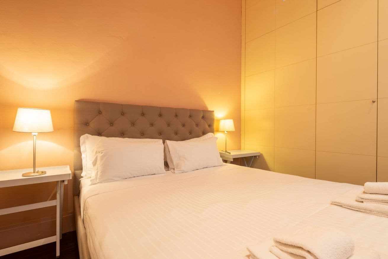 Une chambre d’hôtel avec un grand lit, deux lampes de chevet et une table de nuit.
