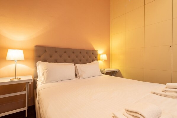 Una habitación de hotel con una cama grande, dos lámparas de noche y una mesita de noche.