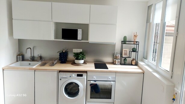 A modern kitchen with a washing machine, oven, and microwave.