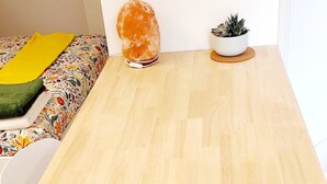 A wooden dining table with white chairs, a salt lamp, and a potted plant on a wooden floor.