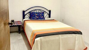 A small, neatly arranged bedroom with a single bed, a bedside table, and a nightstand.