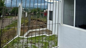 A residential area with a white building, a fenced yard, and a cloudy sky.