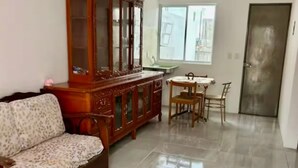 A living room with a sofa, a wooden cabinet, and a dining table with chairs.