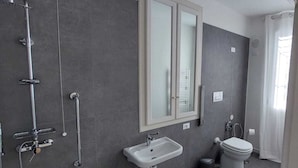 Une salle de bain moderne avec une douche à l’italienne, un lavabo et des toilettes.