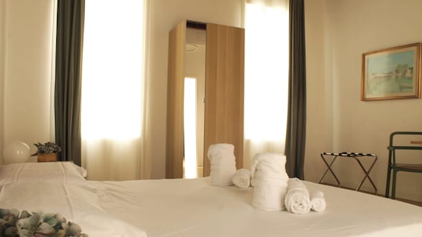 Une chambre d’hôtel avec un lit bien fait, une plante en pot et un tableau accroché au mur.