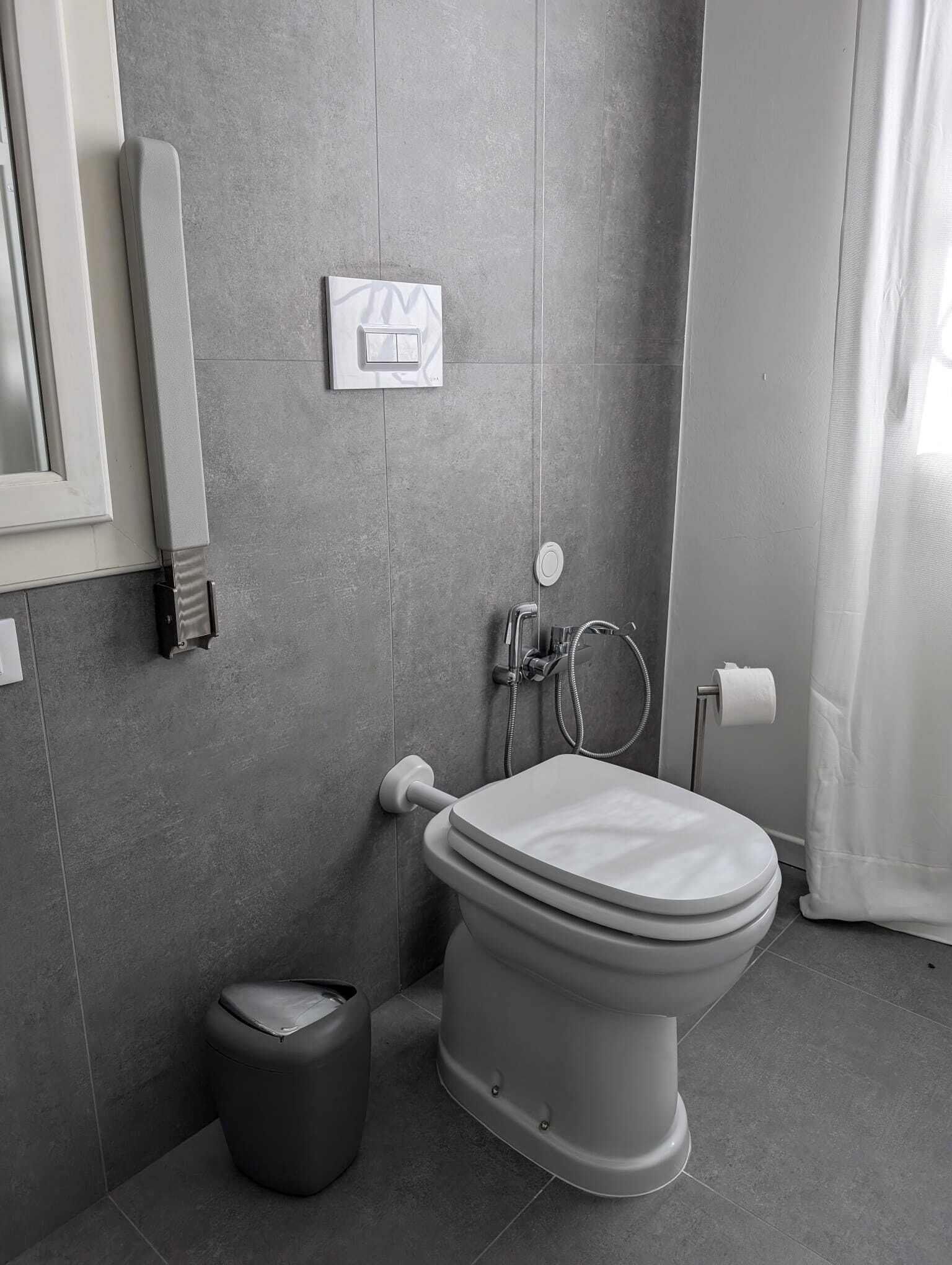 A modern bathroom with a toilet, bidet, and a trash bin.