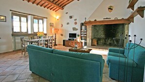 Una sala de estar acogedora con chimenea, un comedor con mesa y sillas, y un televisor.