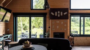 Ein gemütliches Blockhaus-Interieur mit Essbereich, großen Fenstern und Kamin.