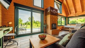 Ein modernes Interieur mit Holzboden, großen Fenstern, einem Kamin und einem Essbereich.