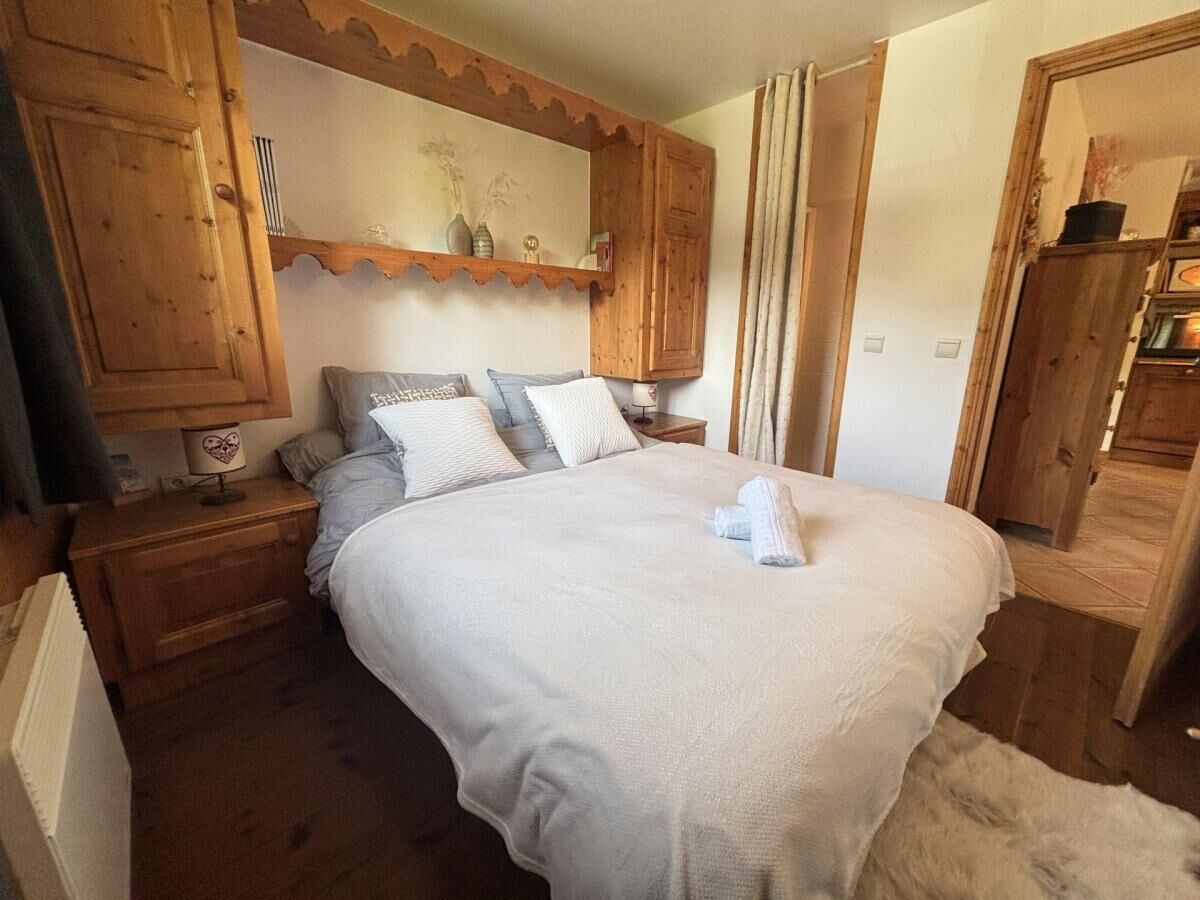 A bedroom with a large bed, wooden headboard, a nightstand, and a dresser.
