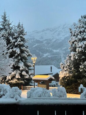 A snow-covered landscape with a wooden cabin and a lamppost.