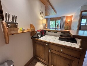Uma cozinha compacta com armários de madeira, painel de azulejos e uma janela que oferece luz natural.