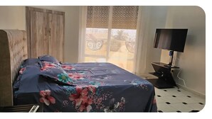 A bed with a floral bedspread, a wooden headboard, and a TV on a stand. - A little jewel in the center of Algiers (El Biar)
