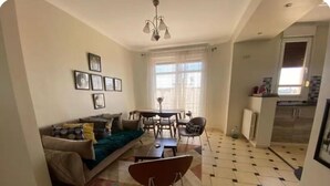 A living room with a sofa, coffee table, and a dining area with chairs and a table. - A little jewel in the center of Algiers (El Biar)