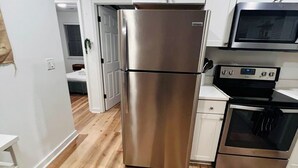 A modern kitchen with stainless steel appliances, white cabinetry, and a wooden floor. - Modern Home w/ Theater, BBQ & Private Yard (Ladson)