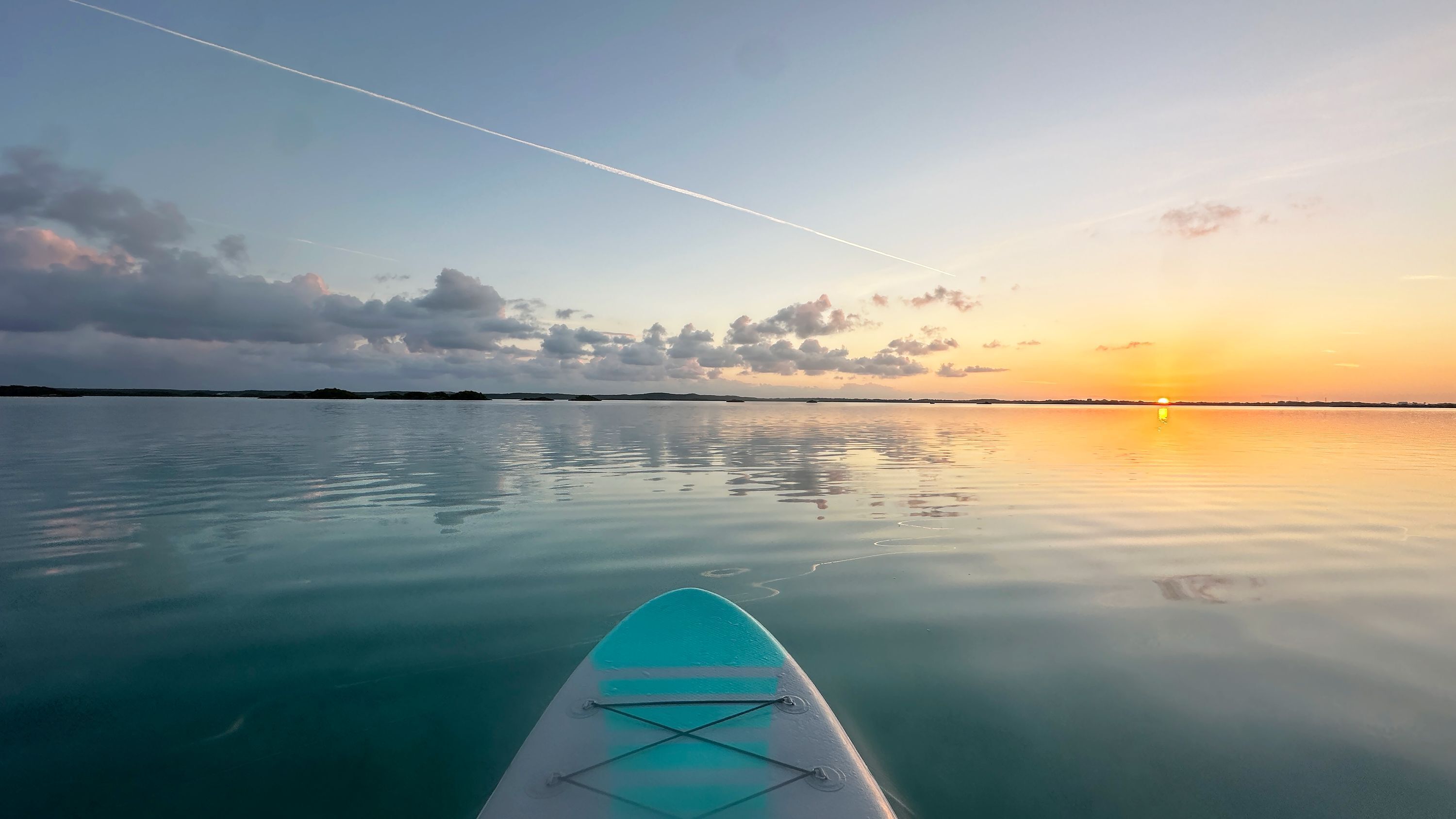 A calm sea with a clear sky and a sunset.