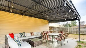 Un patio exterior con una zona de estar cubierta, una mesa y sillas.
