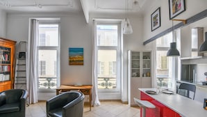 Eine moderne Küche mit roten Akzenten, ein Essbereich mit Tisch und Stühlen sowie ein Blick auf die Stadt durch große Fenster.