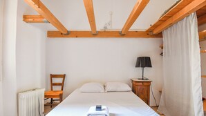 Ein Schlafzimmer mit Bett, Sessel, Nachttisch, Lampe und Heizkörper.
