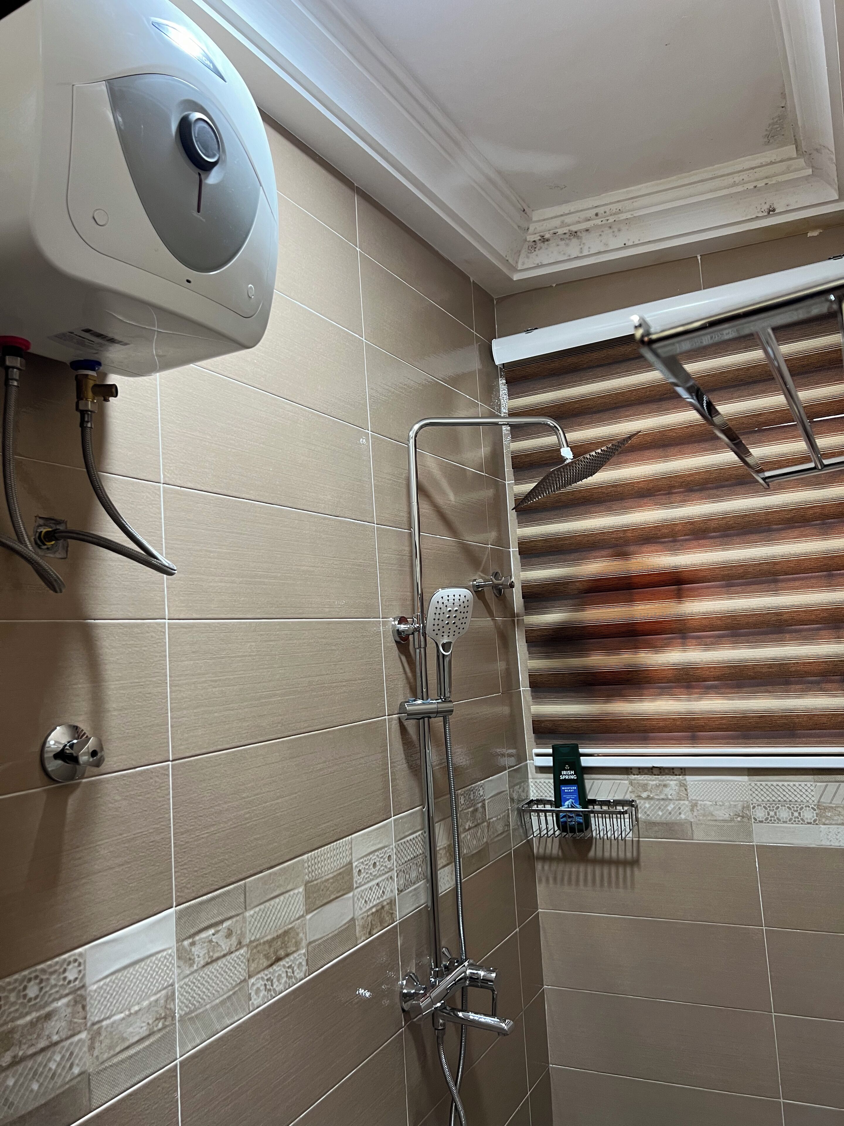 Un baño con ducha, secamanos y barra para toallas.
